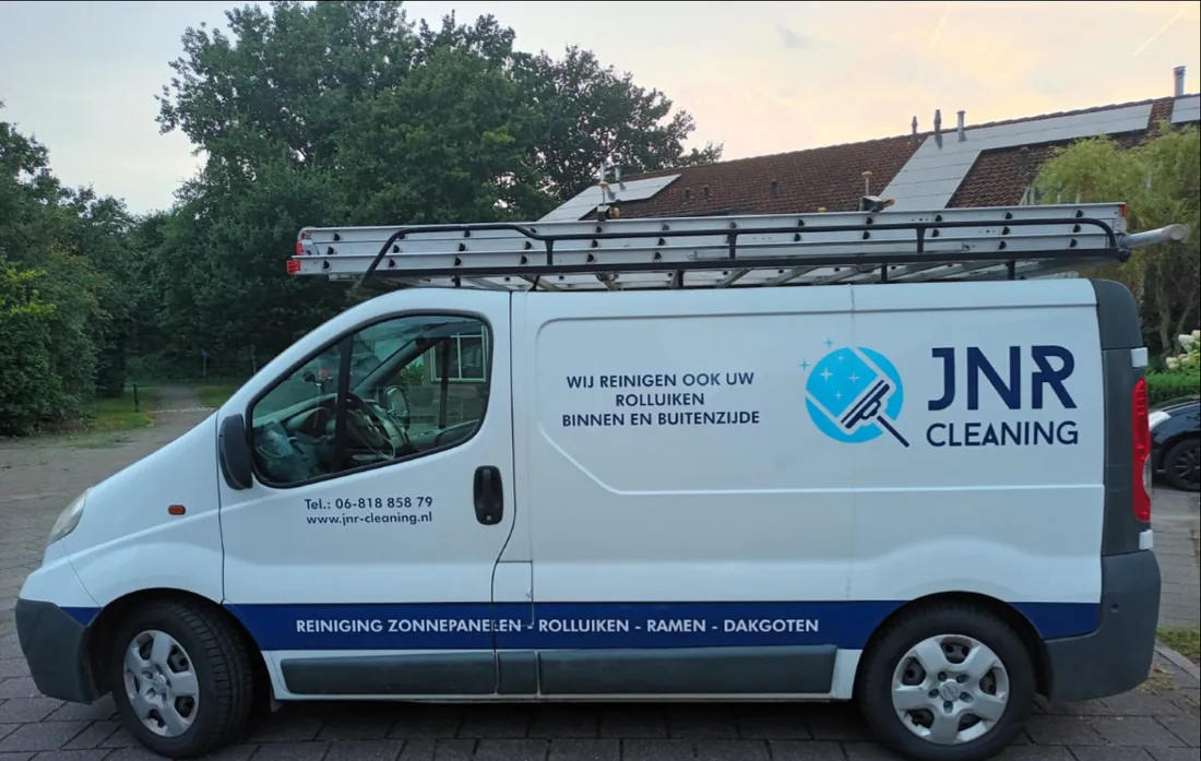 De witte bus van JNR Cleaning met logo en ladders op het dak